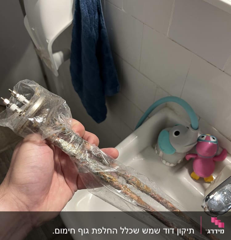 גוף חימום של דוד שמש מוחזק ביד מעל כיור
